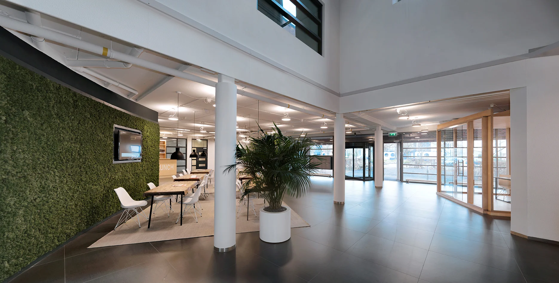 Moderne en lichte kantoorruimte aan de Pompmolenlaan met groene moswand, vergadertafel en glazen entree.