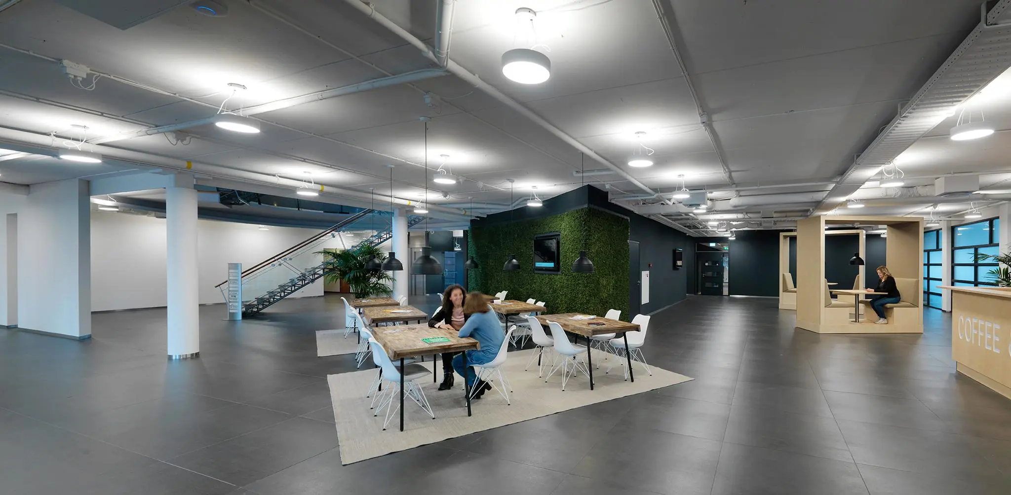 Moderne kantoorlobby aan de Pompmolenlaan met open zitplekken, werktafels en een koffiebar.