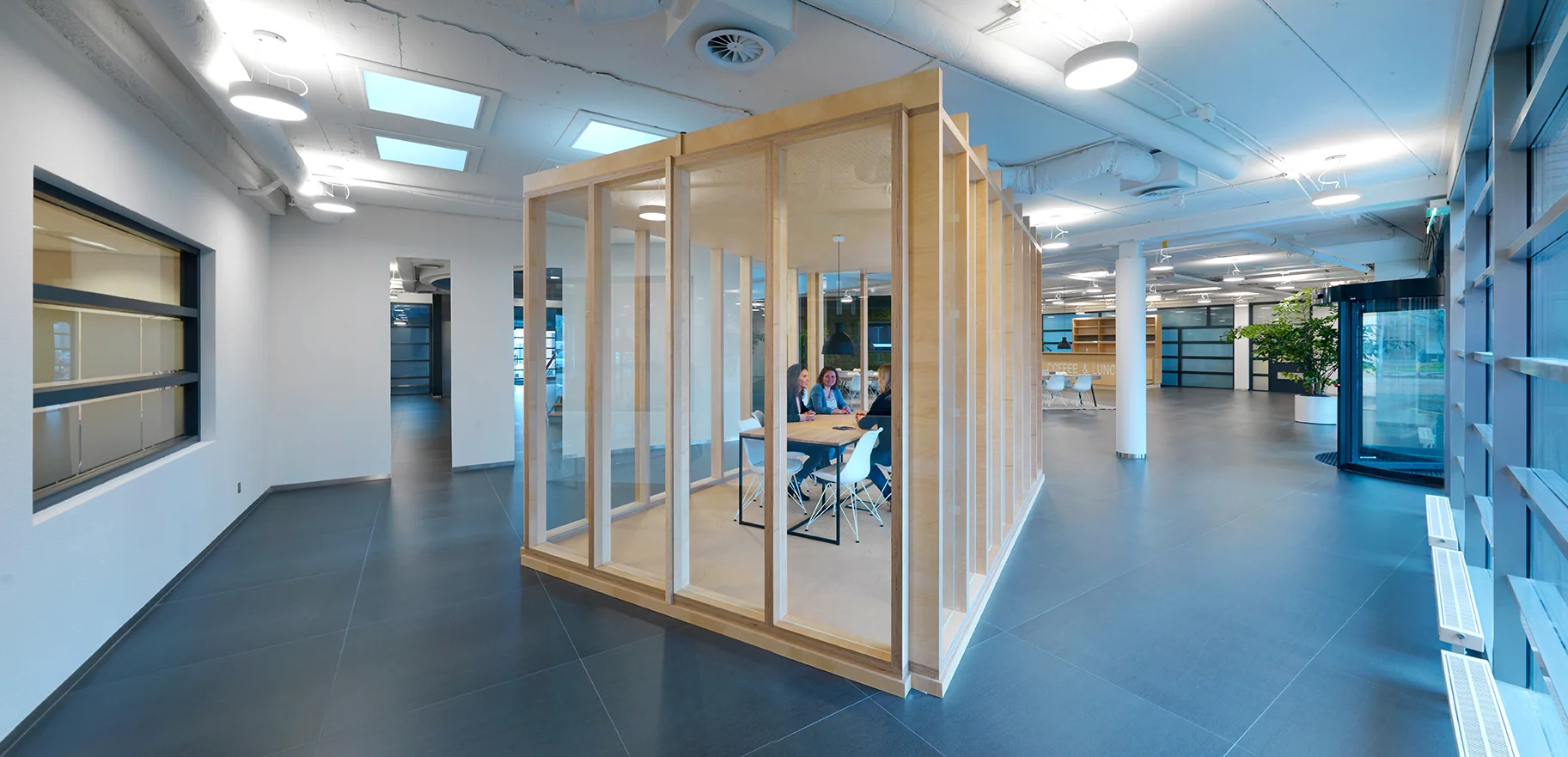 Moderne kantoorlounge aan de Pompmolenlaan met glazen vergaderruimte en open werkruimte.