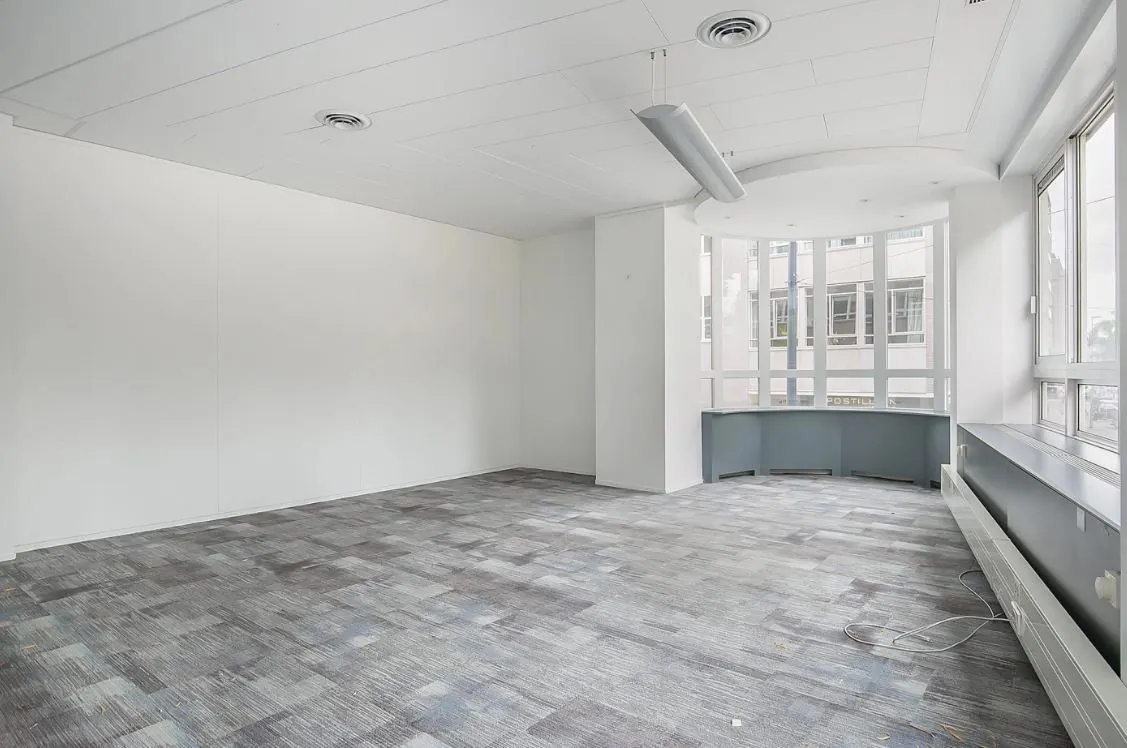 Licht en leeg kantoorruimte in modern gebouw aan de Meent met grote ramen en grijze vloerbedekking.