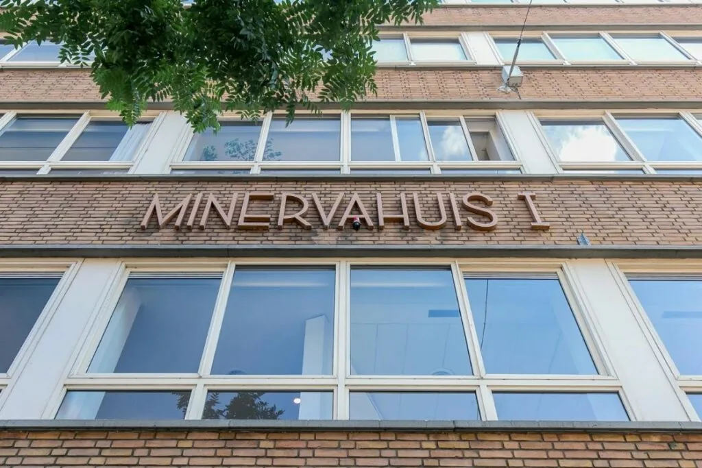 Vooraanzicht van het Minervahuis I met bakstenen gevel en grote ramen.