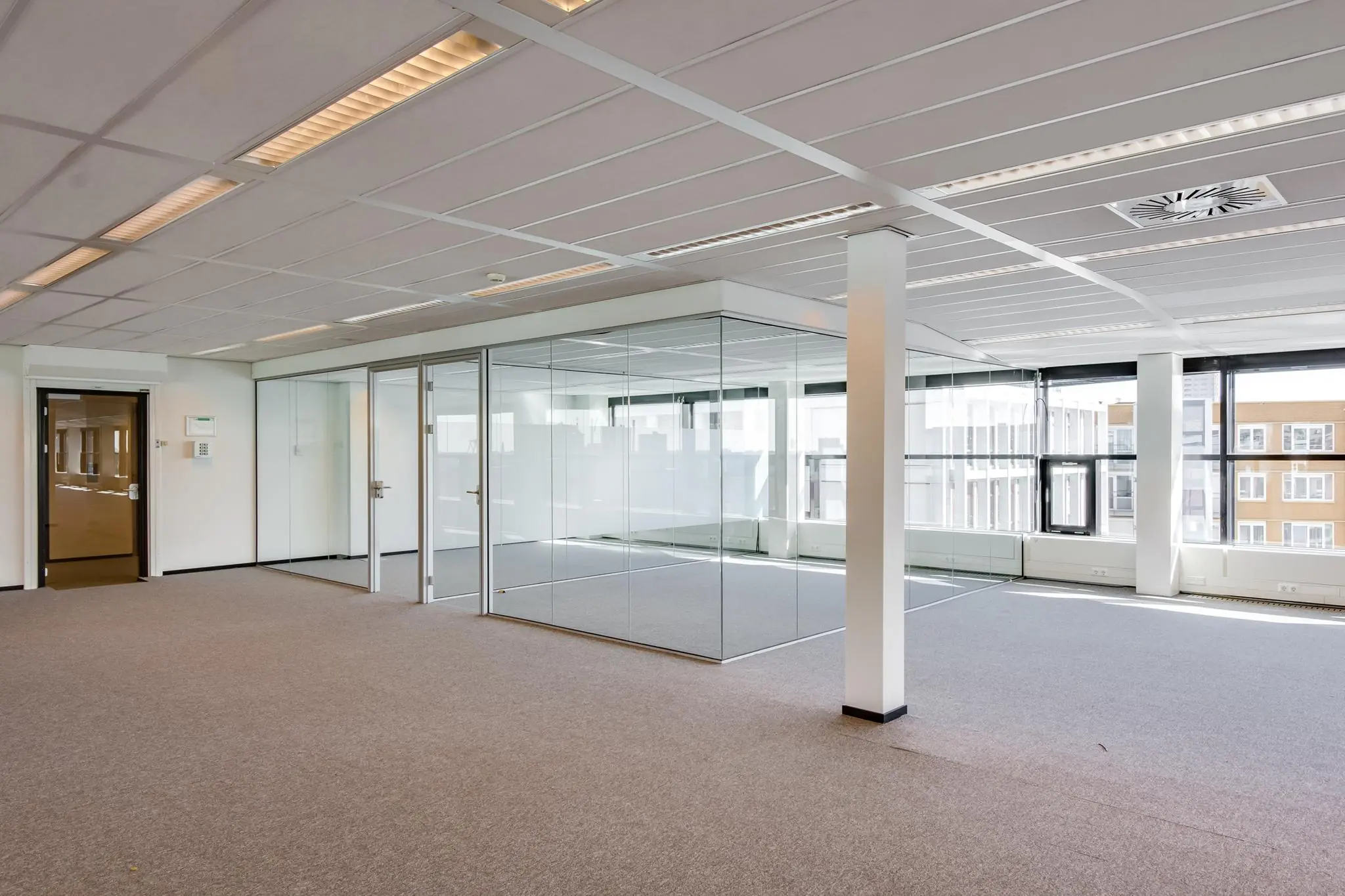 Licht en modern kantoorpand aan de Westerstraat met glazen vergaderruimtes en grote ramen.