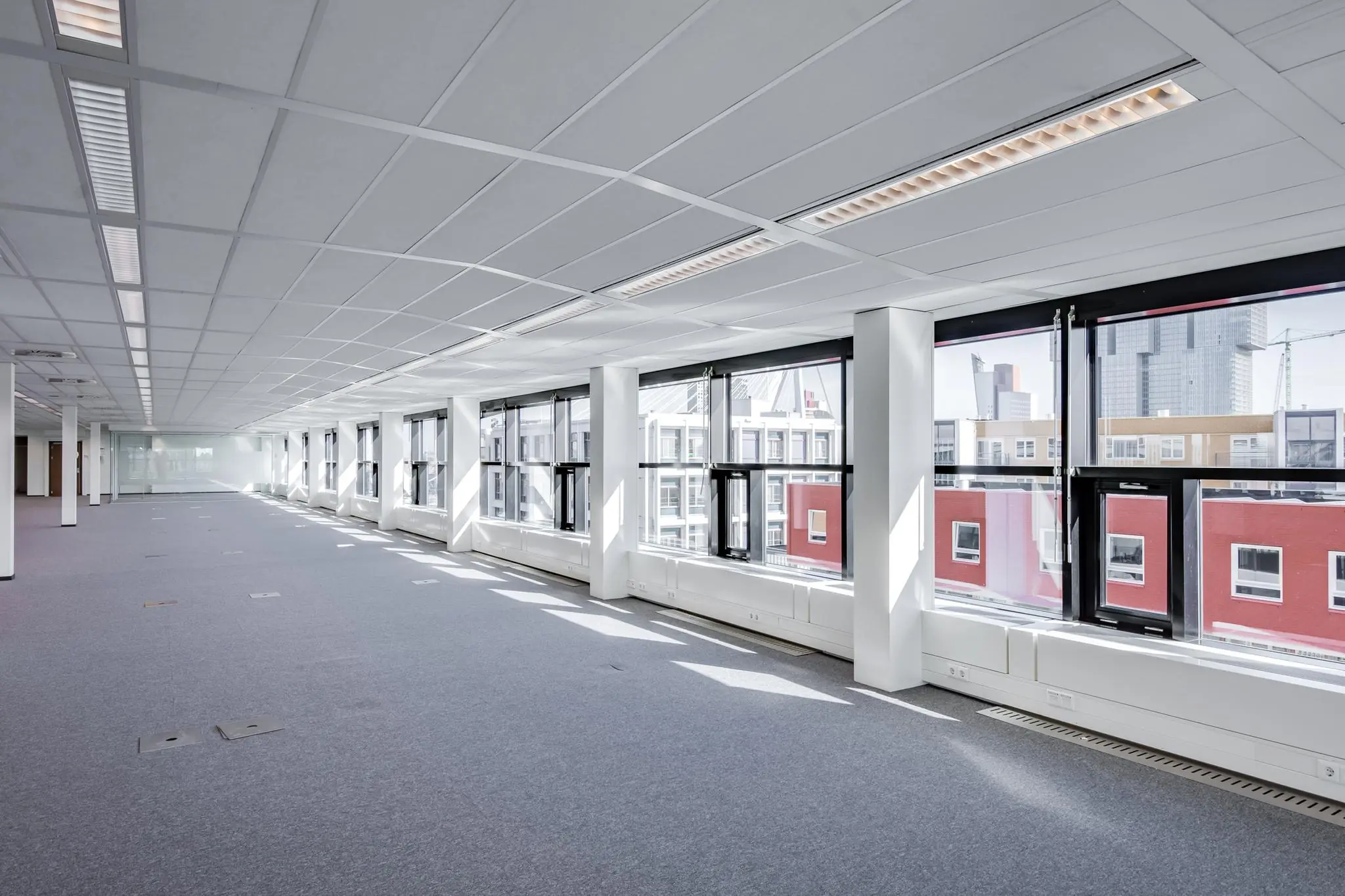 Licht en ruim leeg kantoorpand aan de Westerstraat met grote ramen en zicht op omliggende gebouwen.