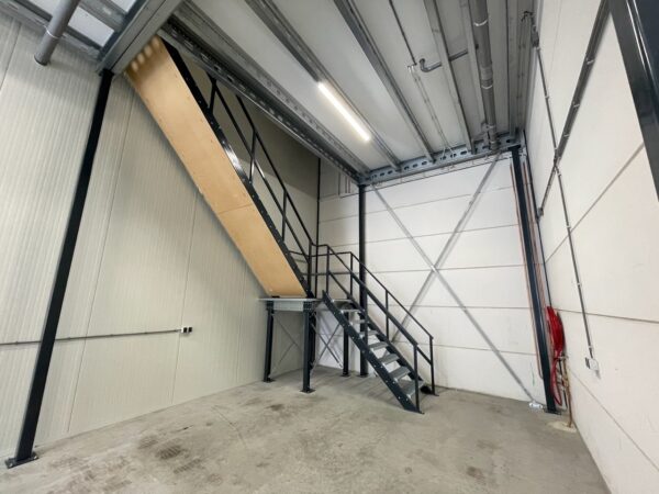 Industriële binnenruimte met een metalen trap naar een entresolvloer aan de Aalsmeerderweg.