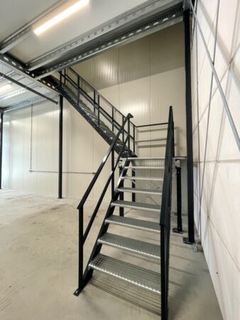 Metalen trap met zwarte leuningen in een industriële ruimte aan de Aalsmeerderweg.