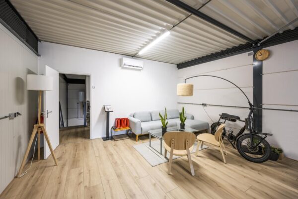 Modern ingerichte wachtruimte aan de Aalsmeerderweg met een bank, designmeubels en een elektrische fiets tegen de muur.