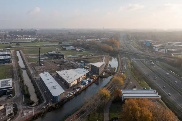 Luchtfoto van de Kringloopweg in een bedrijventerrein met omliggende wegen, waterlopen en gebouwen bij zonsopkomst.