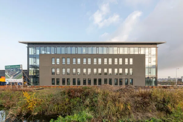 Modern kantoorgebouw aan de Kringloopweg met te huur-bord op een braakliggend terrein.