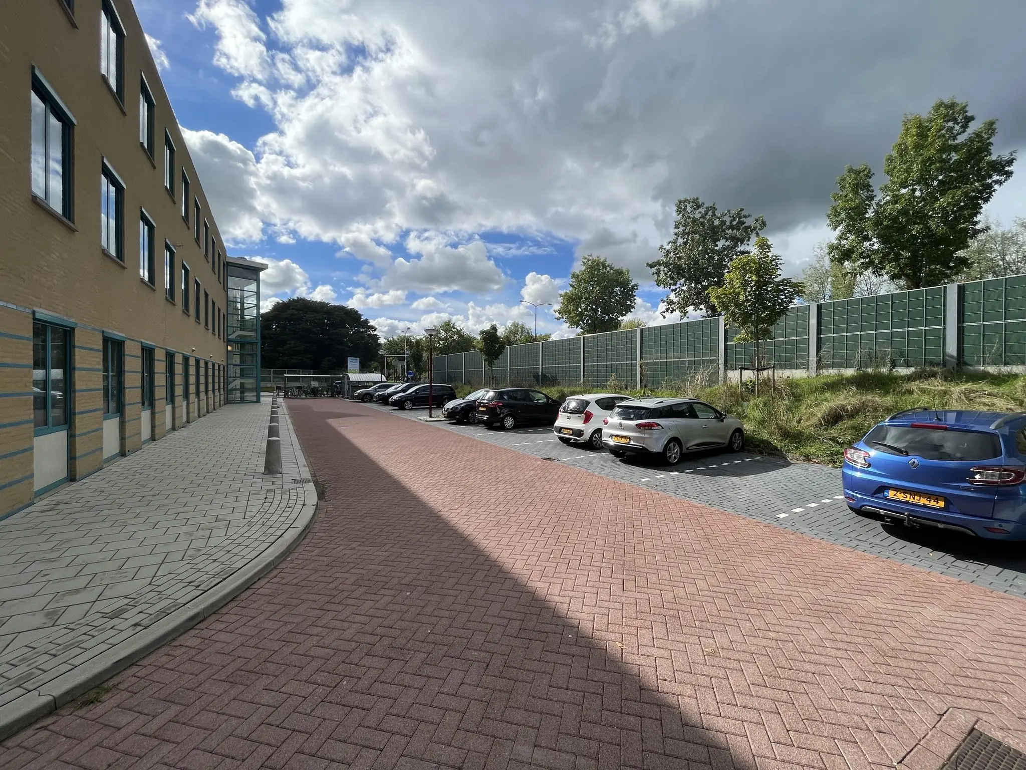 Parkeerplaats en trottoir naast een kantoorgebouw aan de Zoutkamper Schans op een bewolkte dag.