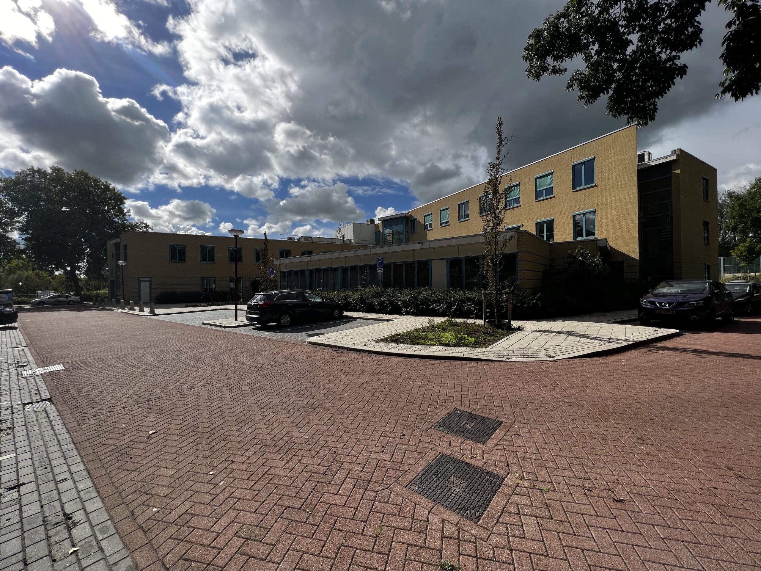 Een modern gebouw met parkeerplaatsen ervoor, onder een bewolkte hemel in Zoutkamperschans.