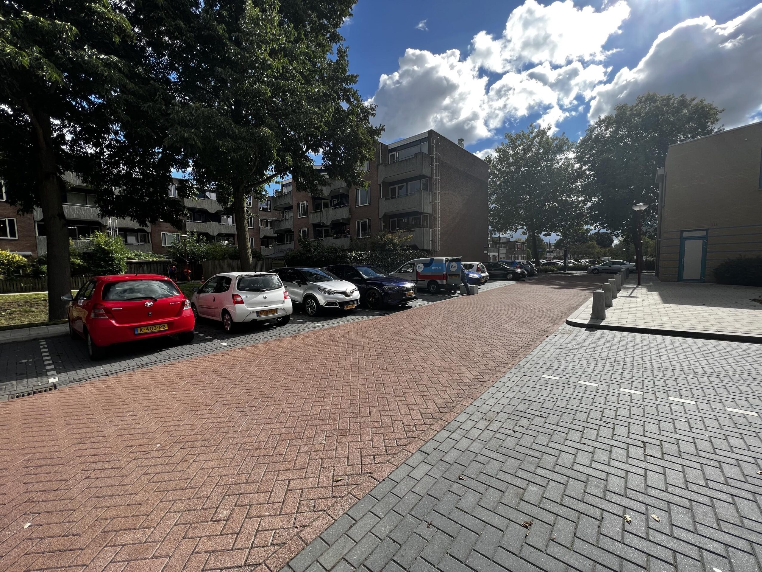 Parkeerplaats bij Zoutkamperschans met auto's en omringende appartementen onder een deels bewolkte hemel.
