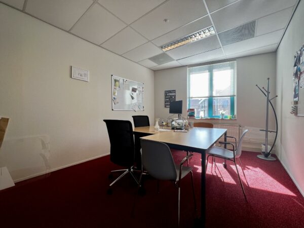 Kantoorruimte in Zoutkamperschans met vergadertafel, stoelen, prikborden en een raam met zonlicht.