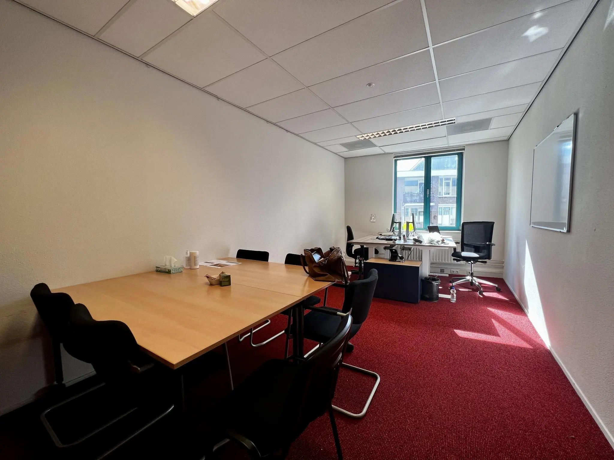 Kantoorruimte aan de Zoutkamper Schans met vergadertafel, bureaus en rood tapijt.