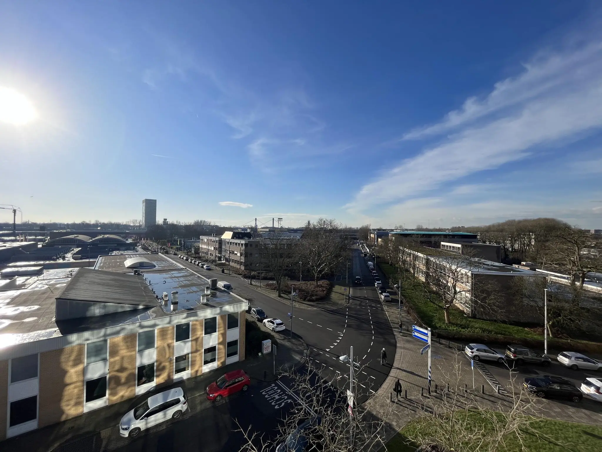 Luchtfoto van de Australielaan in een stedelijk gebied met autoverkeer, gebouwen en een heldere blauwe lucht.