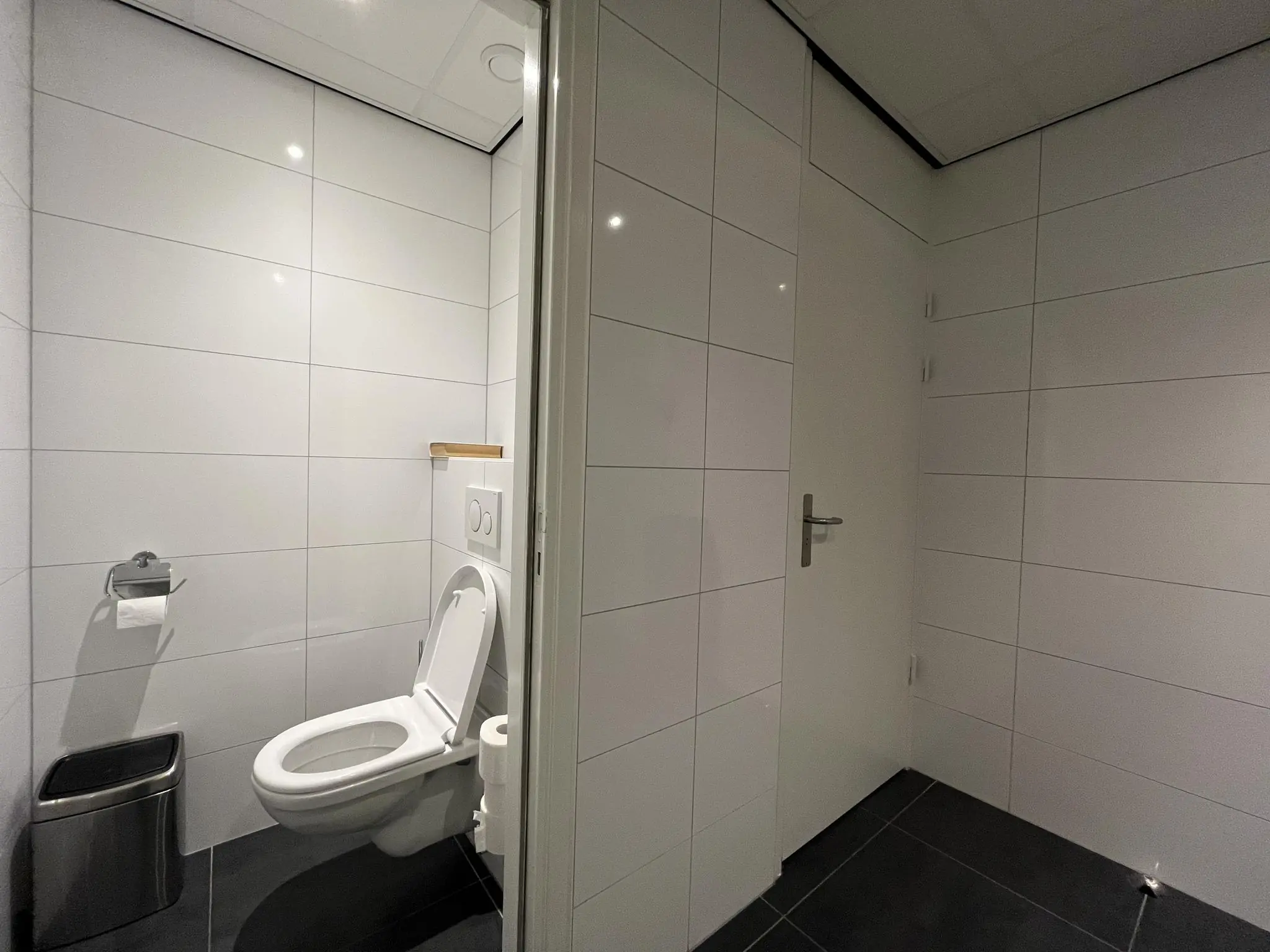 Modern betegelde toiletruimte met hangtoilet, toiletrolhouder en prullenbak aan de Australielaan.