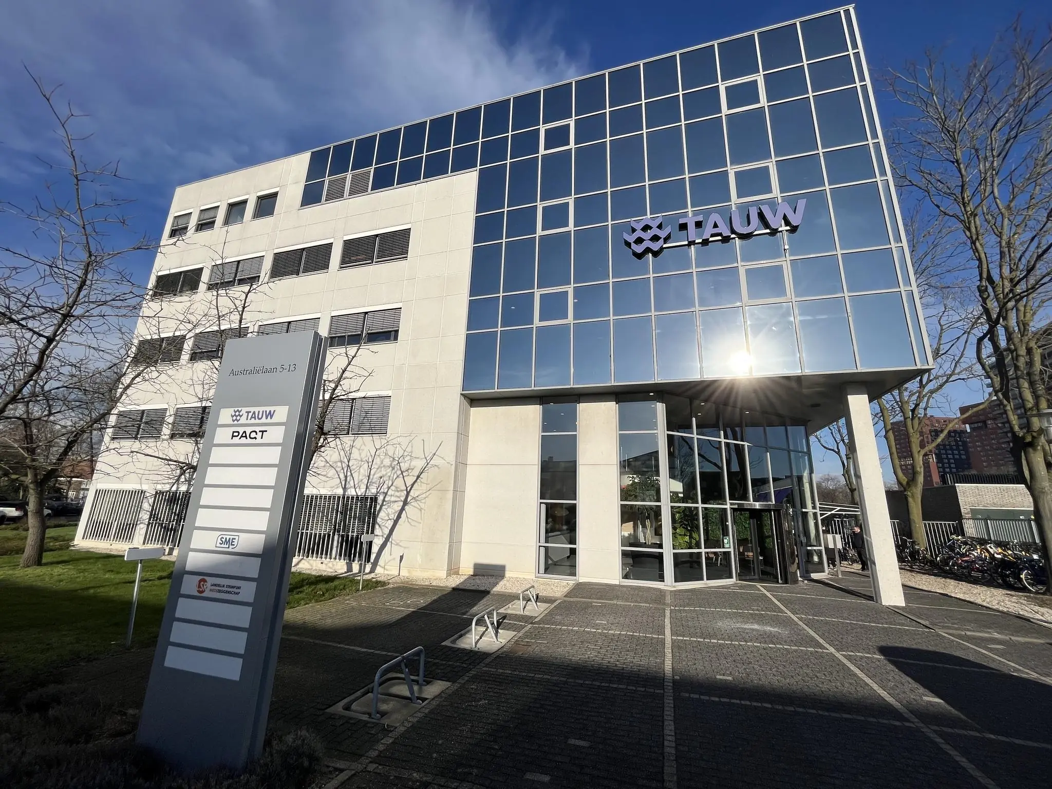 Kantoorgebouw aan de Australiëlaan 5-13 met het logo van TAUW op de gevel en een bedrijvenbord op de voorgrond.