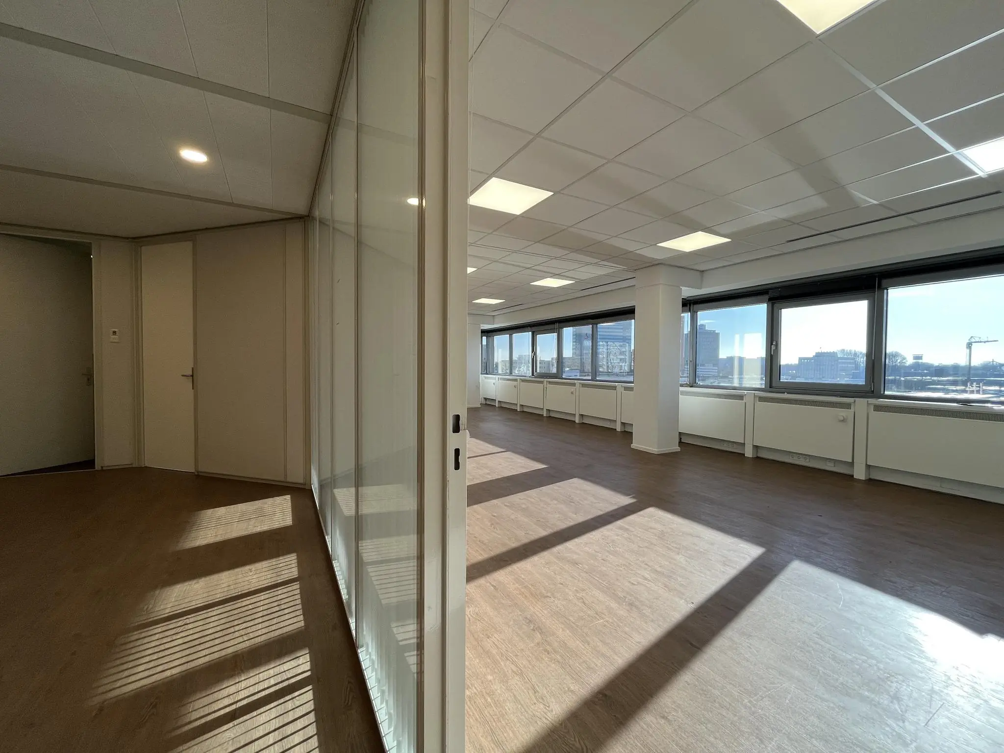 Licht en modern kantoorinterieur aan de Australiëlaan met grote ramen en glazen scheidingswand.