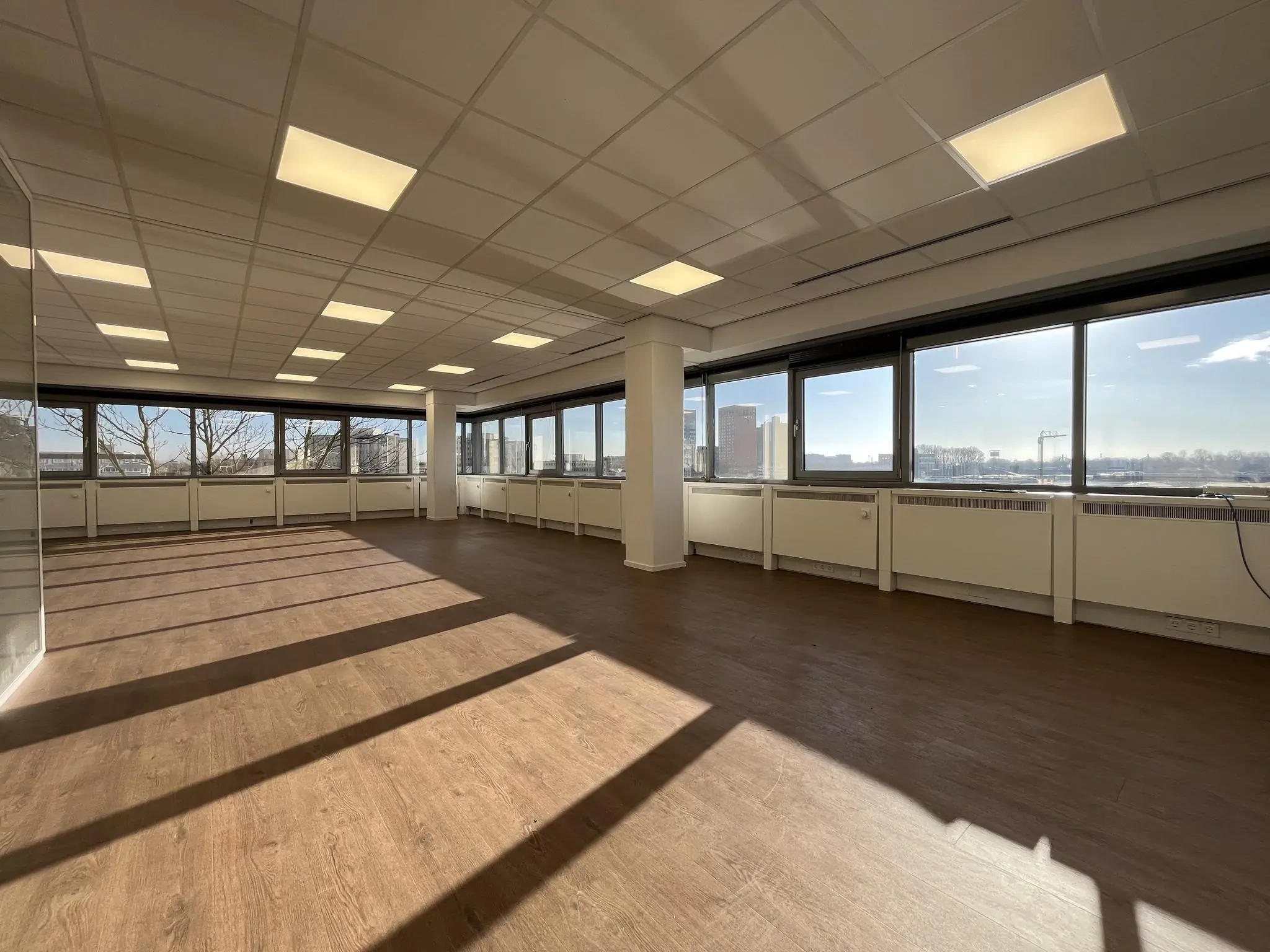 Lichte, lege kantoorruimte aan de Australielaan met grote ramen en uitzicht op de skyline.