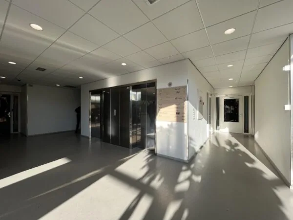 Inkomhal met liften en bewegwijzering in een modern kantoorgebouw aan de Australiëlaan.