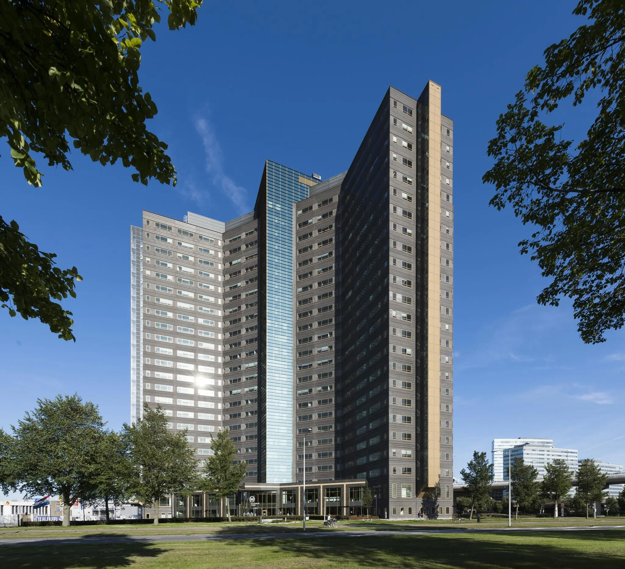 Hoog modern kantoorgebouw aan de Radarweg in Amsterdam, omgeven door groen en een blauwe lucht.