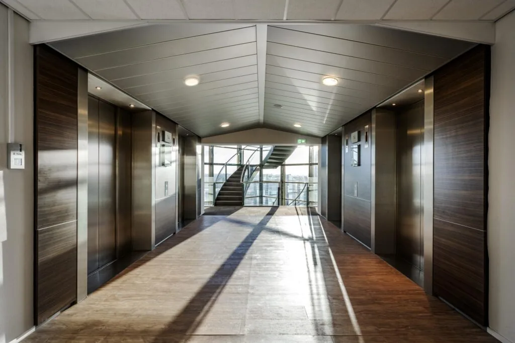 Lichte en moderne liftlobby op de 14e verdieping van het kantoorgebouw aan de Radarweg, met zicht op een glazen trappenhuis.
