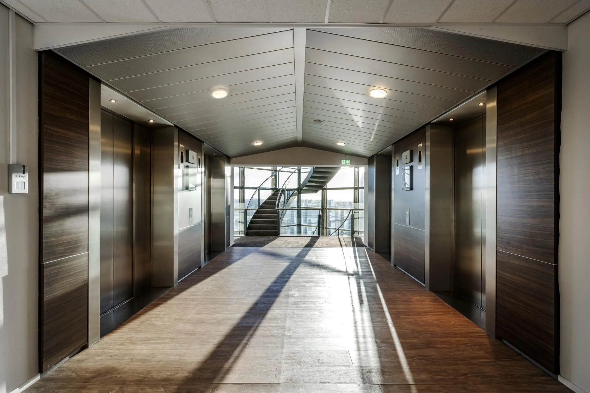 Lichte en moderne liftlobby op de 14e verdieping van het kantoorgebouw aan de Radarweg, met zicht op een glazen trappenhuis.