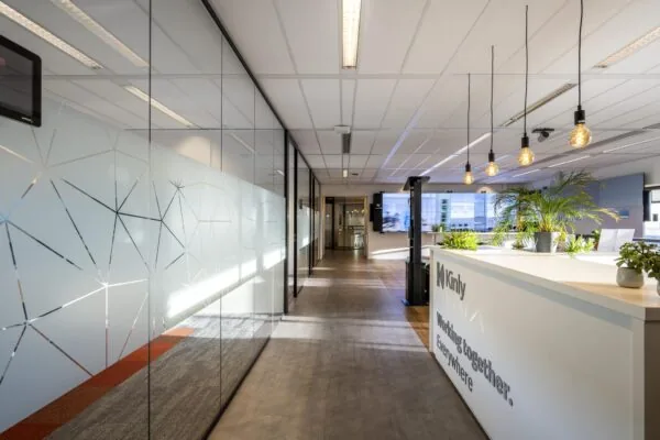 Moderne kantoorruimte aan de Radarweg met glazen wanden, planten en een receptiebalie van Kinly.