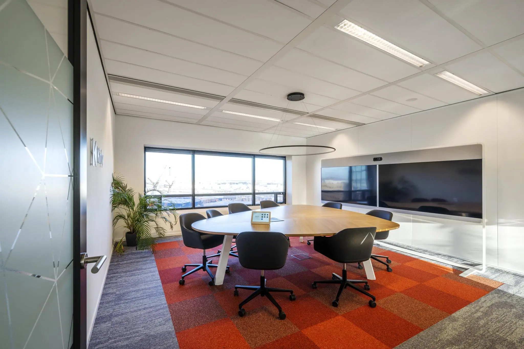 Moderne vergaderruimte op Radarweg met ovale tafel, zes stoelen, groot videoscherm en panoramisch raam.