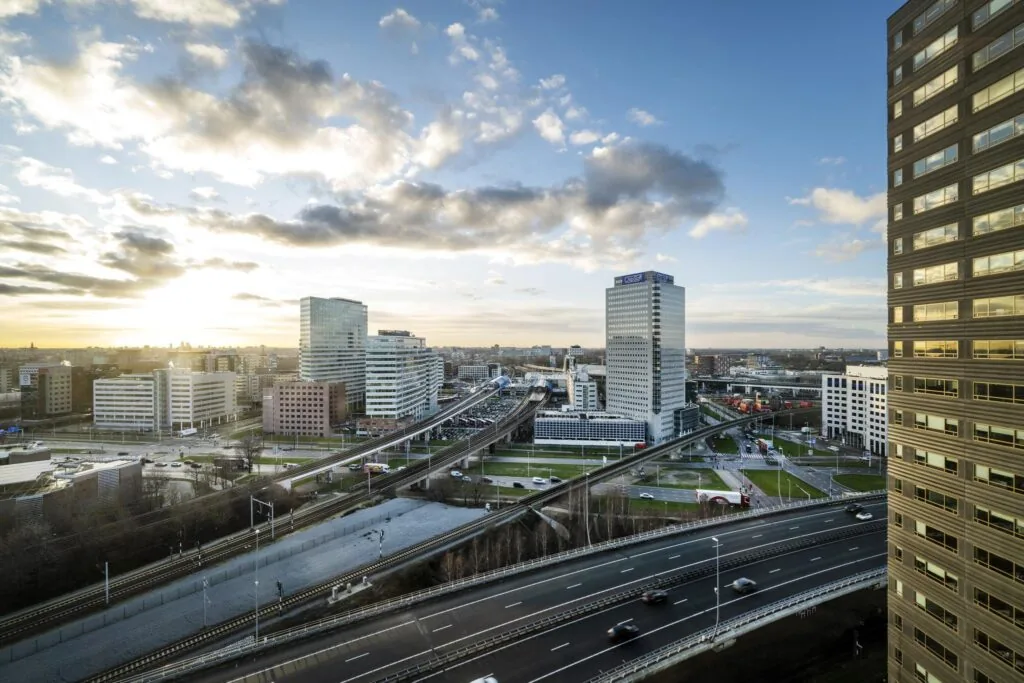 Uitzicht op kantoren en infrastructuur rond de Radarweg in Amsterdam bij zonsondergang.