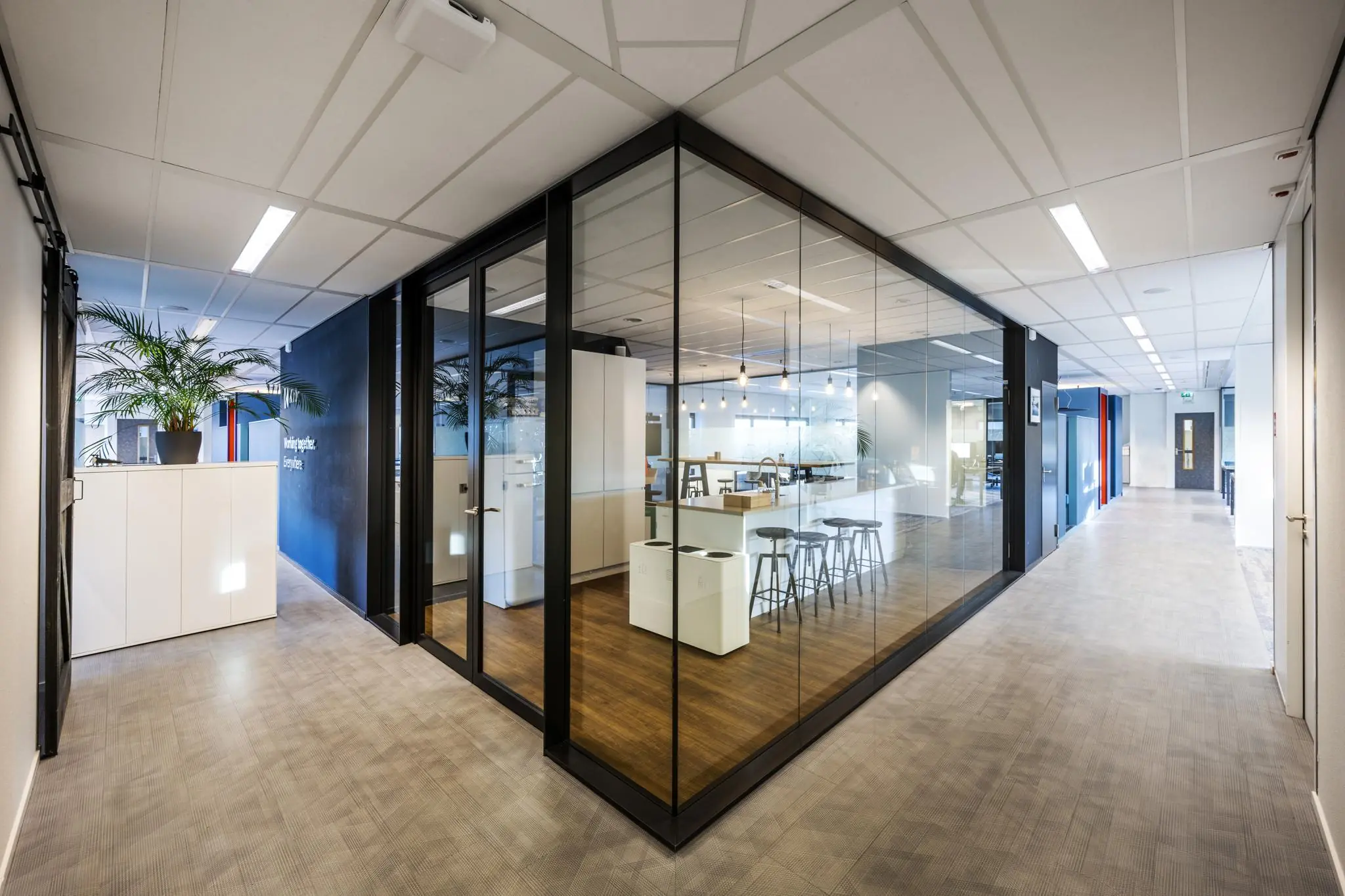 Modern kantoorinterieur aan de Radarweg met glazen vergaderruimte, hoge tafels en strakke afwerking.