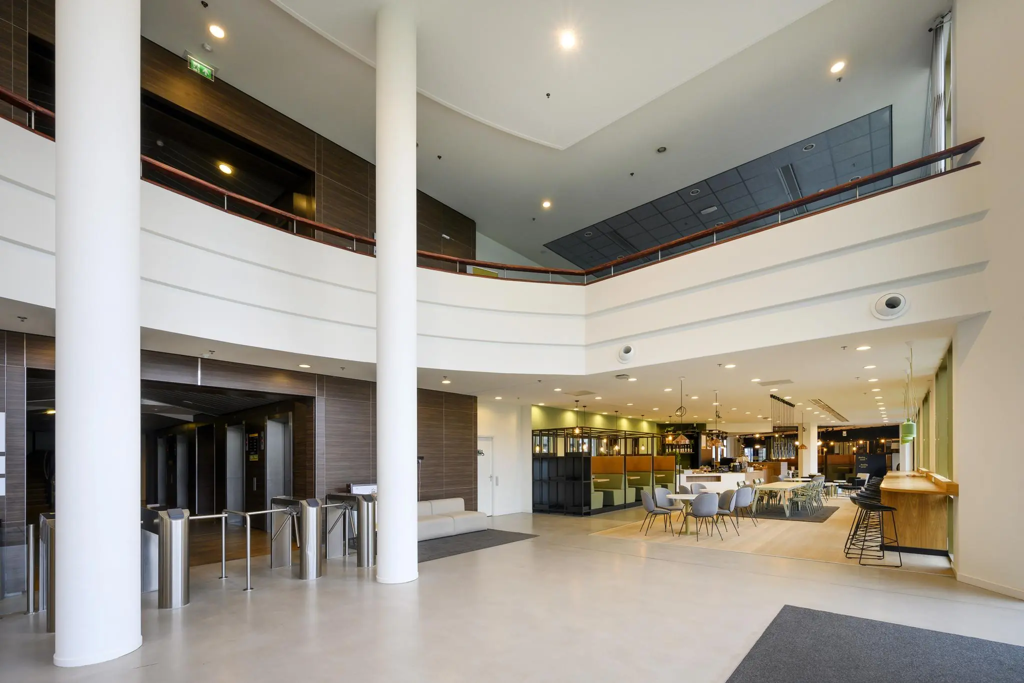 Moderne en ruime ontvangsthal van een kantoorgebouw aan de Radarweg, met zitgedeelte, liften en toegangspoortjes.