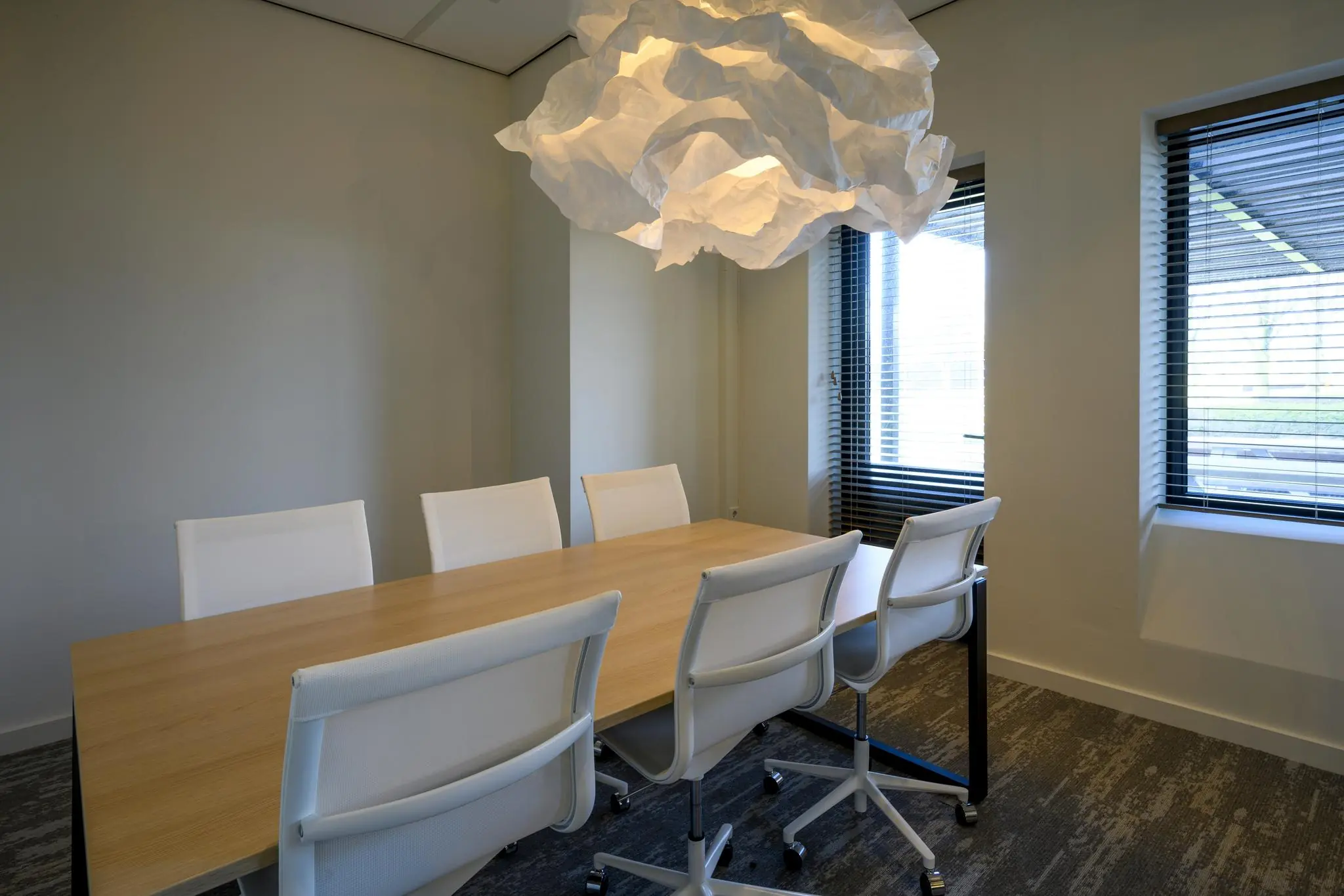 Vergaderruimte aan de Radarweg met houten tafel, zes witte stoelen en een opvallende wolkvormige hanglamp.