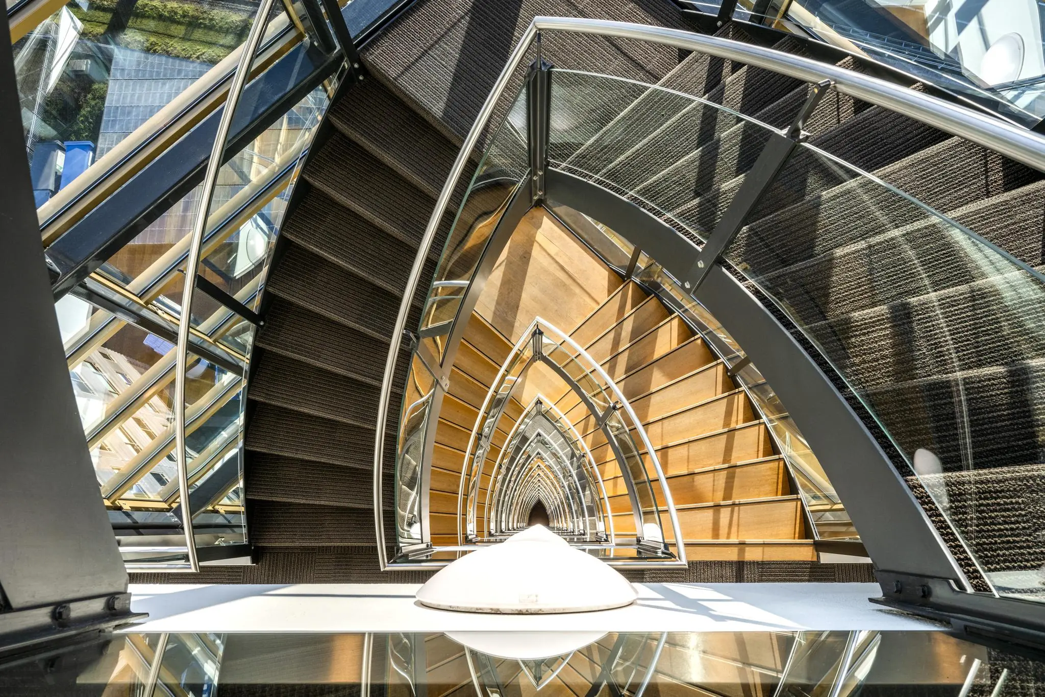 Spiraalvormige houten trap met metalen leuningen in het gebouw aan de Radarweg, gezien van bovenaf.