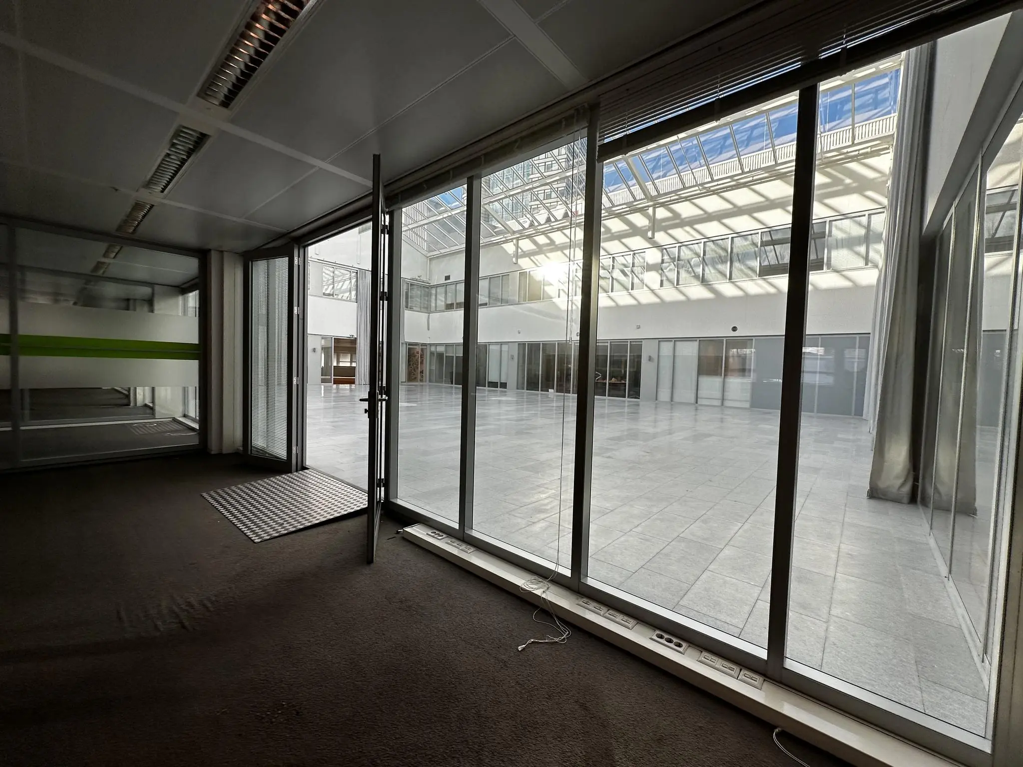 Glazen deur en ramen in een kantoorpand aan de Europalaan met uitzicht op een licht atrium met glazen dak.