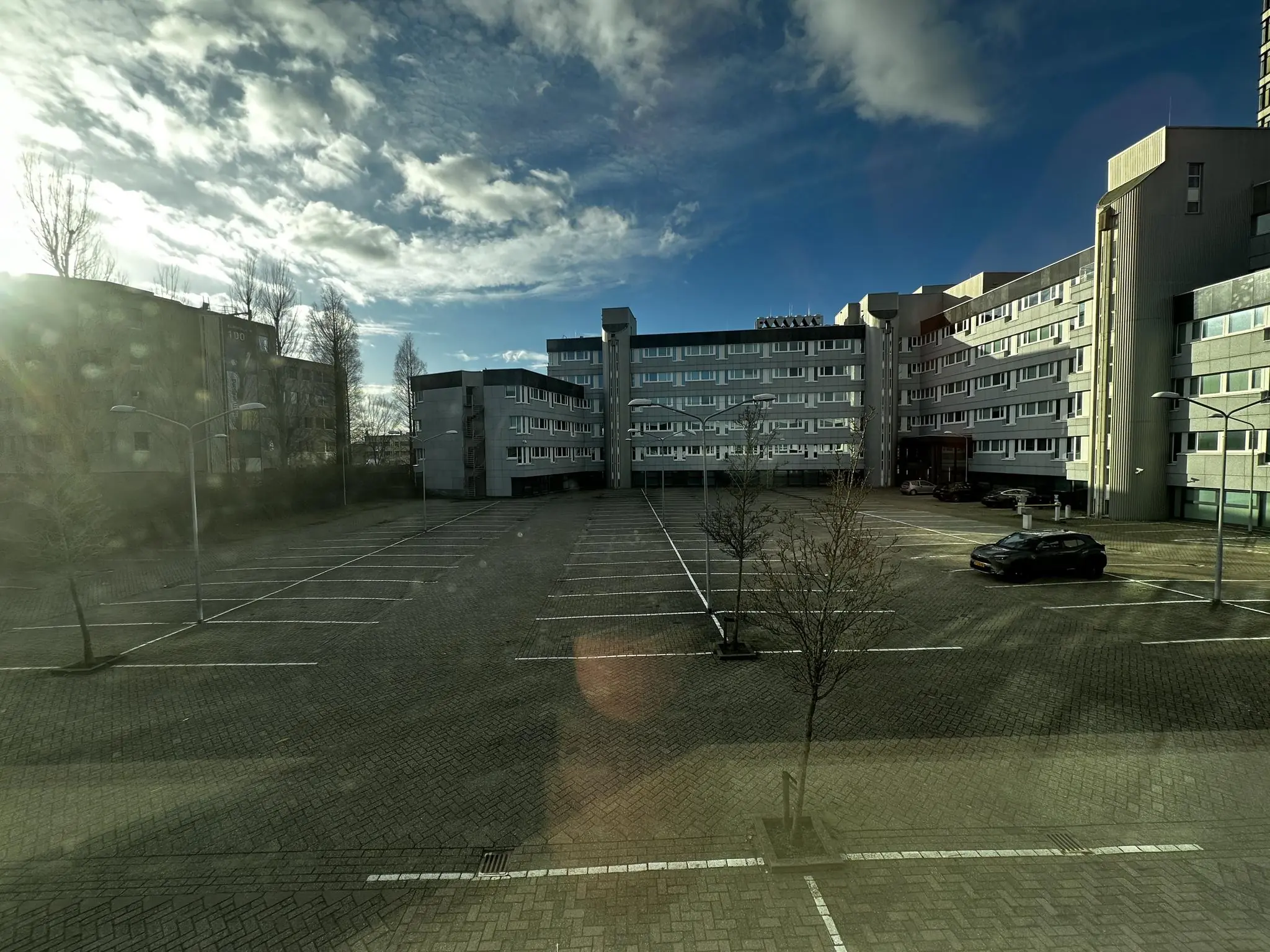 Leeg parkeerterrein aan de Europalaan met een enkele geparkeerde auto en een omringend kantoorgebouw.