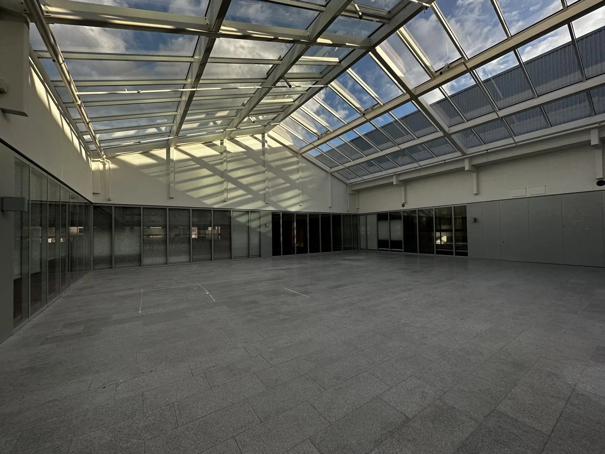 Lichte, overdekte binnenruimte aan de Europalaan met glazen plafond en omliggende glazen kantoormuren.