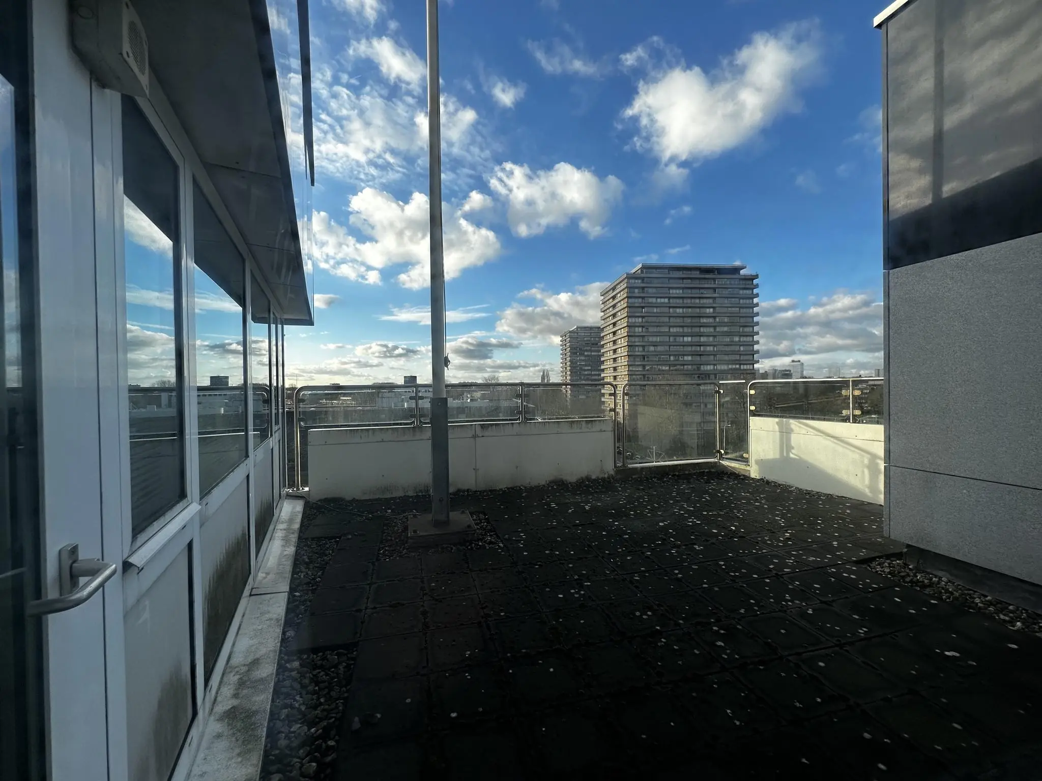 Uitzicht vanaf een dakterras aan de Europalaan met hoogbouw en een deels bewolkte blauwe lucht.