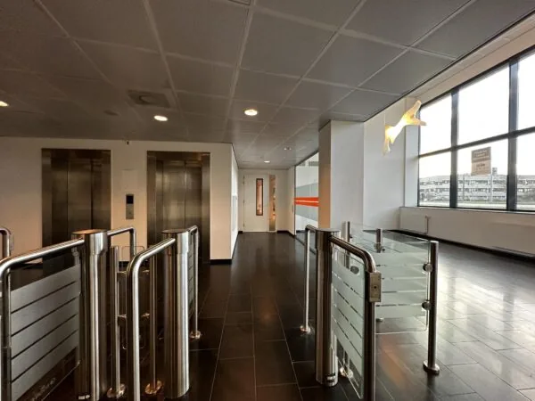 Ingang van een modern kantoorgebouw aan de Europalaan met tourniquets, liften en grote ramen.