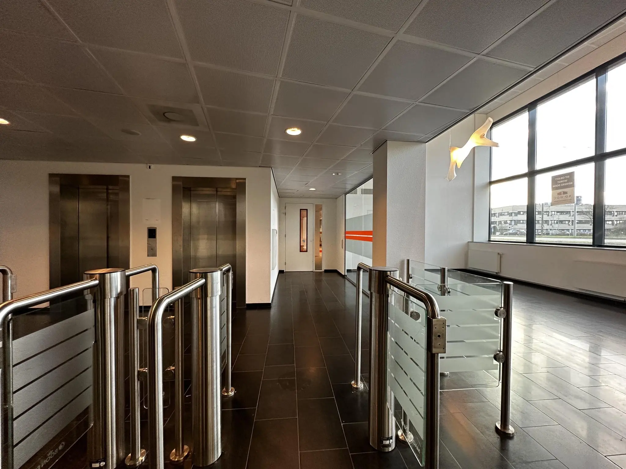 Ingang van een modern kantoorgebouw aan de Europalaan met tourniquets, liften en grote ramen.