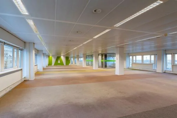 Leeg kantoorpand aan de Europalaan met grote ramen en systeemplafond.