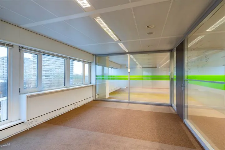 Lege kantoorruimte aan de Europalaan met grote ramen en glazen wanden met groene accenten.