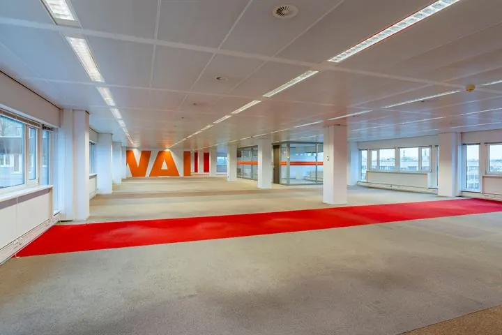 Leeg kantoorpand aan de Europalaan met grote ramen, systeemplafond en rood tapijtvloerpad.