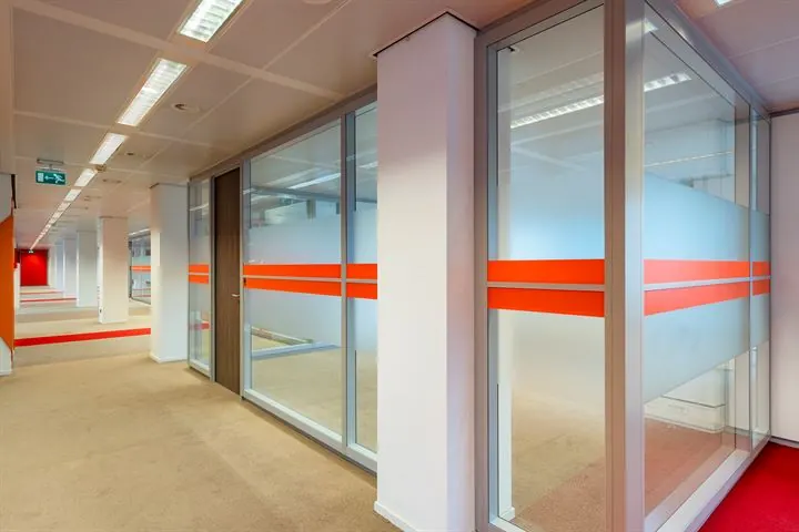 Moderne kantoorruimte aan de Europalaan met glazen vergaderruimtes en rood-witte decoratieve accenten.