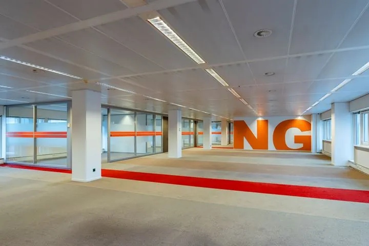 Kantoorruimte aan de Europalaan met glazen wanden, rood vloeraccent en grote oranje letters "NG" op de achterwand.