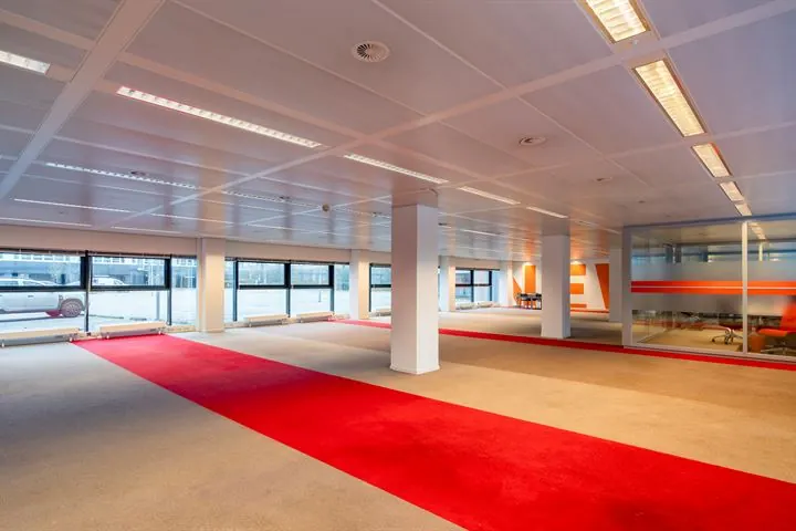 Licht en ruim kantoorpand aan de Europalaan met grote ramen en opvallend rood tapijt.