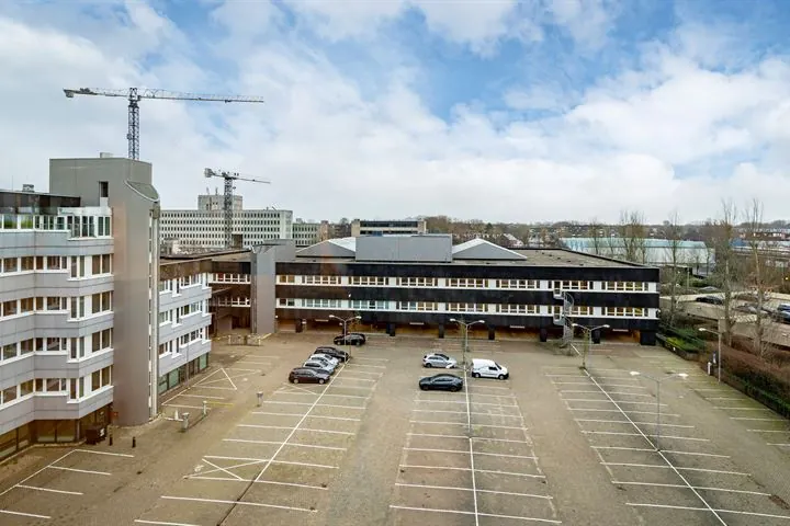 Leeg parkeerterrein aan de Europalaan met enkele geparkeerde auto's en kantoorgebouwen op de achtergrond.