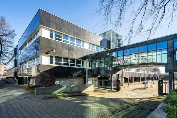 Modern kantoorgebouw aan de Eendrachtlaan met glazen loopbrug en parkeerterrein op de voorgrond.