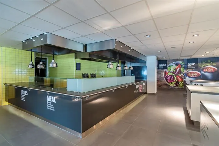 Moderne bedrijfskantine aan de Eendrachtlaan met strakke uitgiftebalie en felle gele tegels op de achterwand.