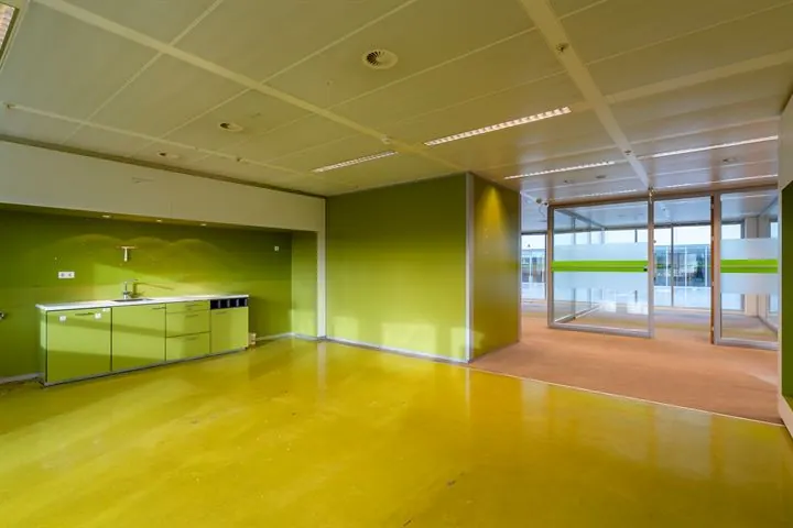 Moderne, lege kantoorruimte aan de Eendrachtlaan met groene wanden, kitchenette en glazen scheidingswanden.
