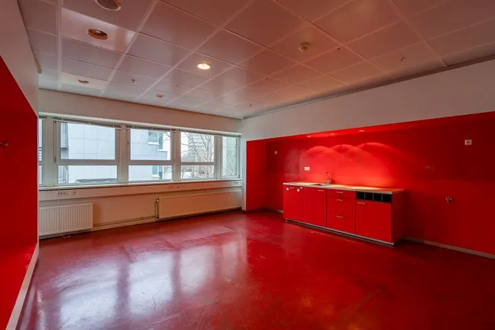 Lege kantoorruimte aan de Eendrachtlaan met rood vloer- en wandontwerp en een kleine keukenunit.